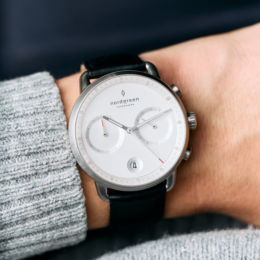 Worn on a wrist beside a gray knit sweater, white dial facing forward.