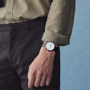 Side view of a man in an olive shirt with the dark-cased watch on his wrist.