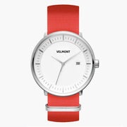 Watch with a white dial and silver-tone case on a bright red woven strap.