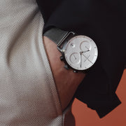 Hand in a trouser pocket showing the watch against a black jacket sleeve.