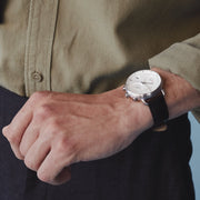 A man in an olive shirt wearing the white dial watch on a black strap.