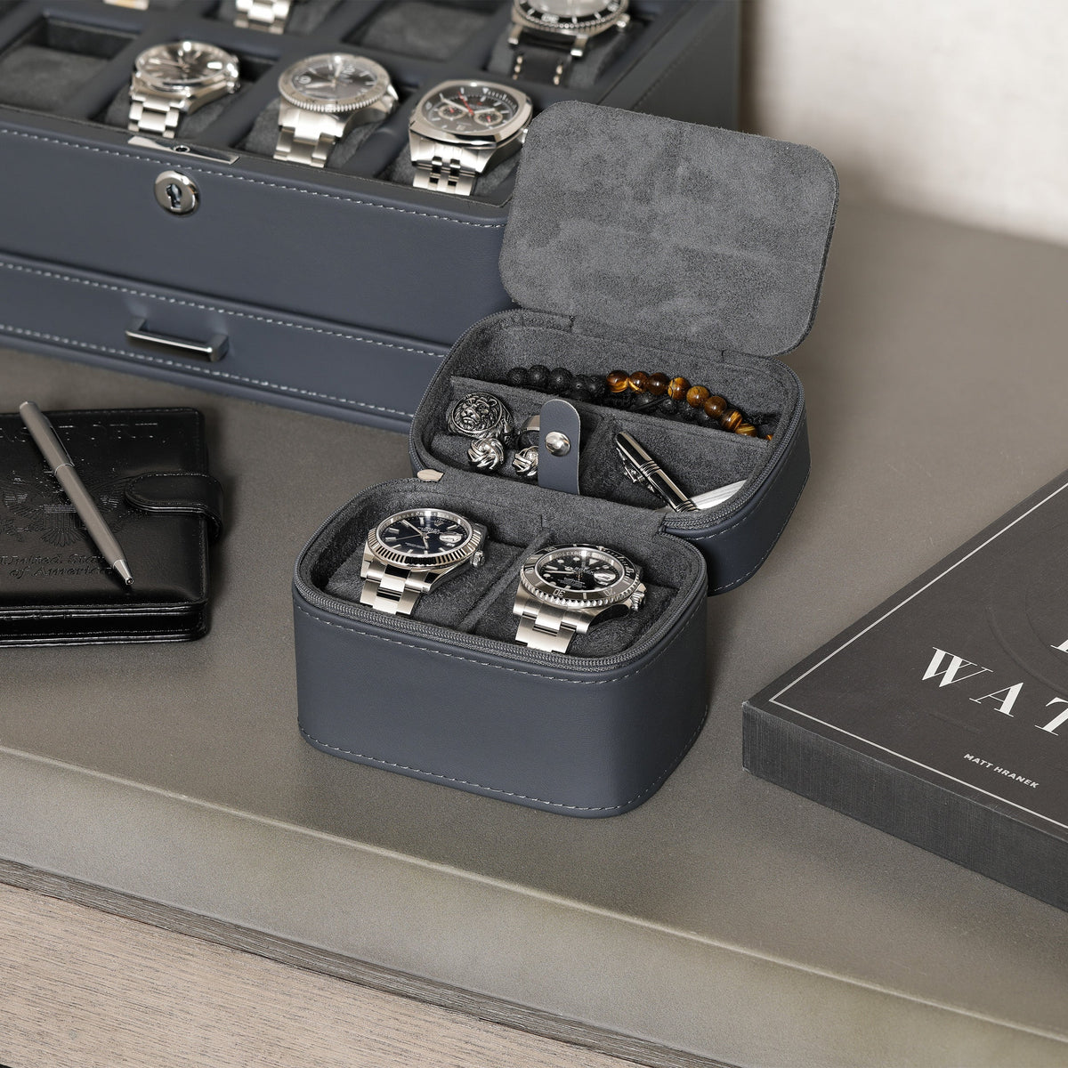 Two-watch travel case open next to a watch box and wallet