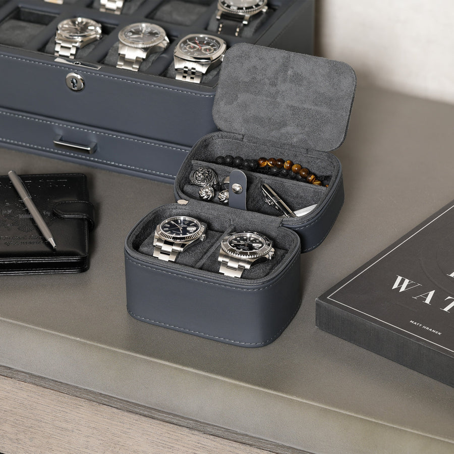 Two-watch travel case open next to a watch box and wallet