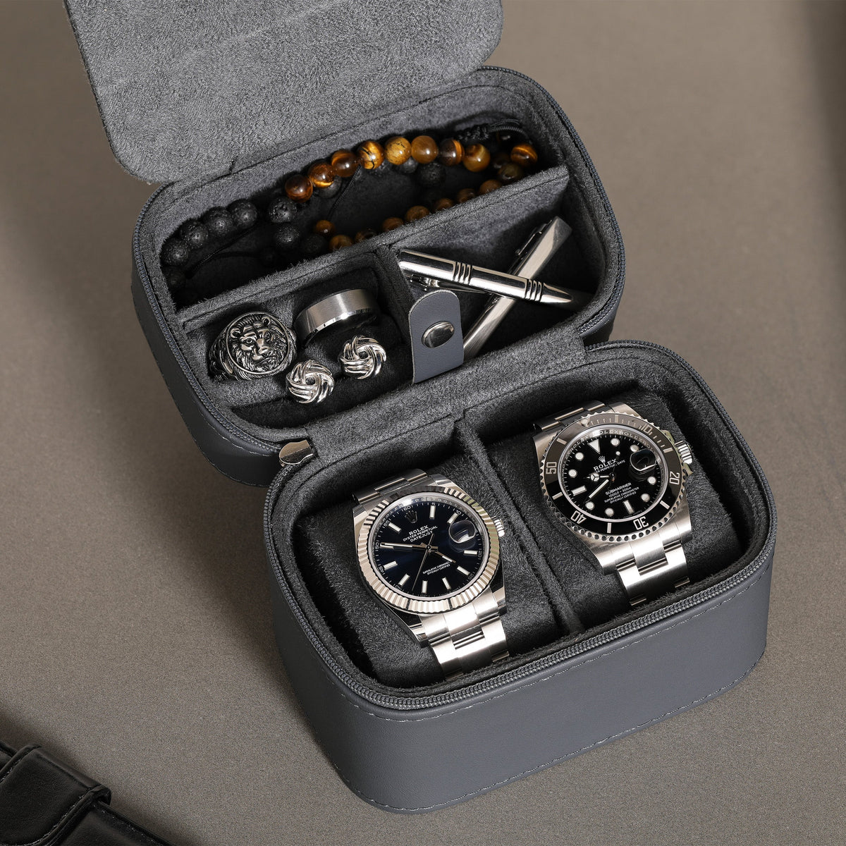 Close-up of two watches on cushions with accessories in the lid