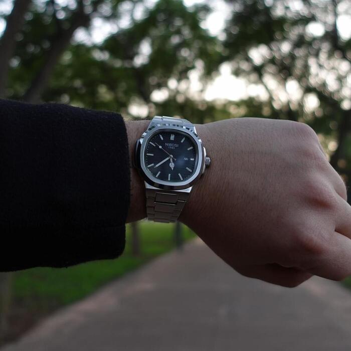 Blue dial watch on a wrist outdoors