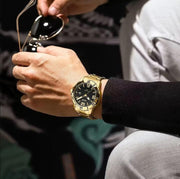 Gold-tone watch on the wrist with sunglasses