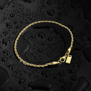 Gold-tone rope chain on a wet black surface