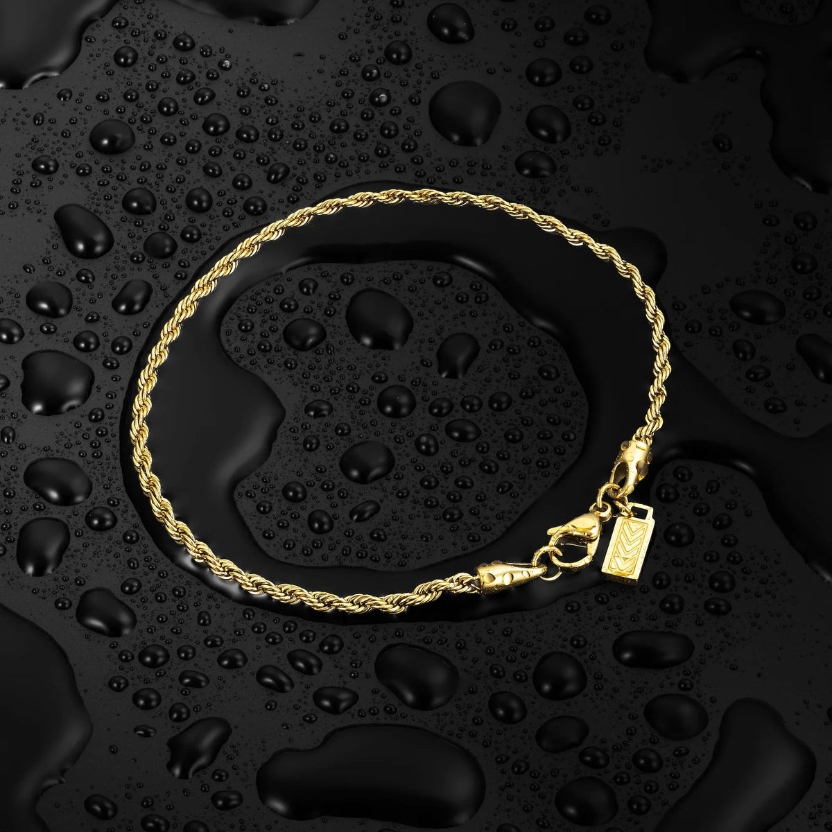 Gold-tone rope chain on a wet black surface