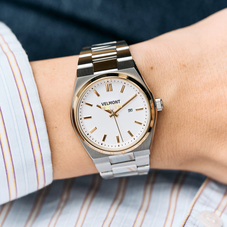 The two-tone watch worn on a wrist with a striped shirt cuff.