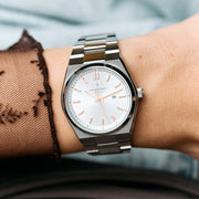 The silver-tone watch on a wrist under a sheer black lace sleeve.