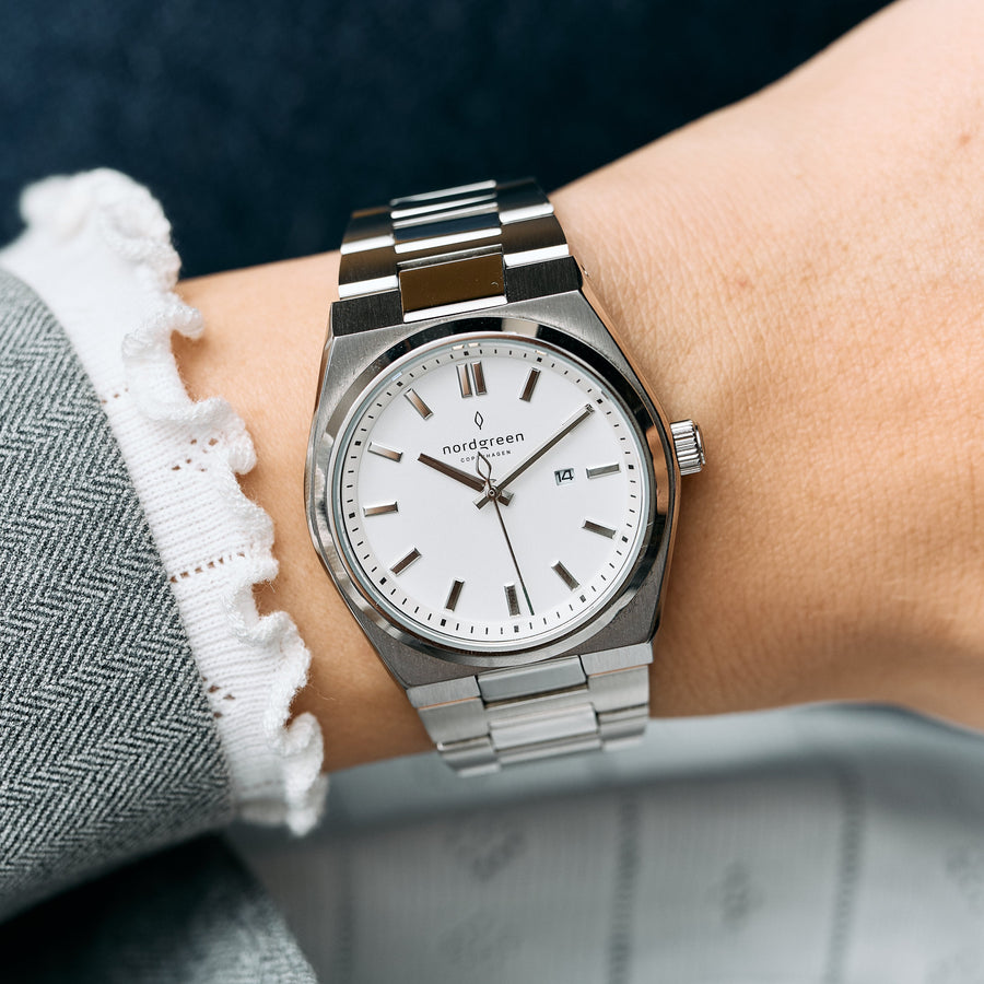 Worn on a wrist with a ruffled cuff, showing the white dial and date.