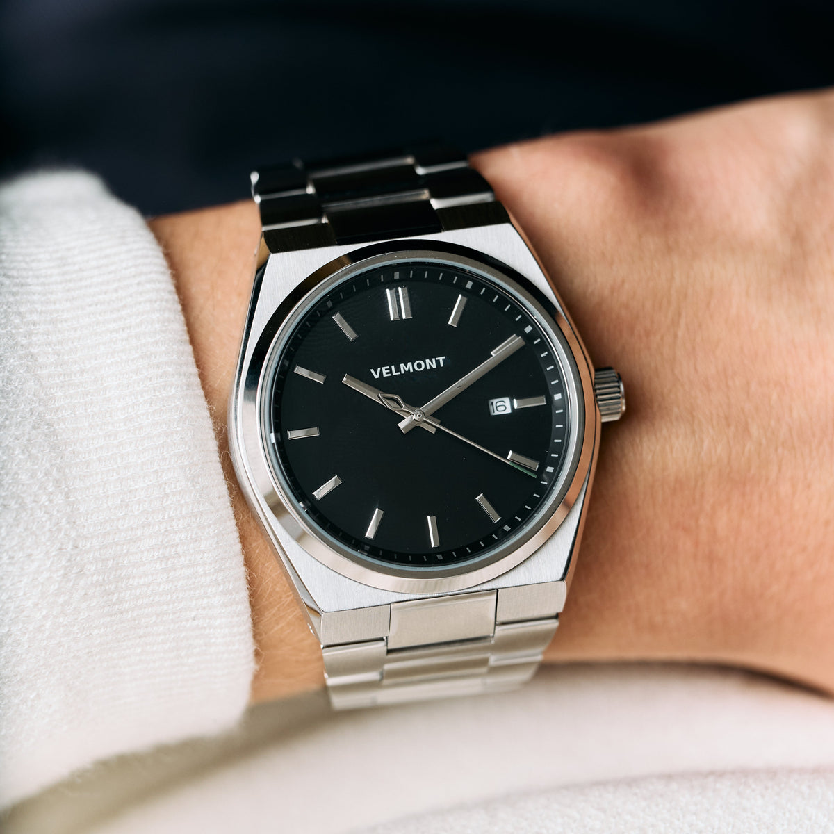 The watch worn on a wrist, paired with a white knit sleeve.