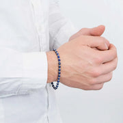 Beaded bracelet worn with a white shirt, hands clasped