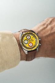 Yellow chronograph on the wrist with a brown strap