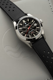 Black dial watch on black strap at an angle