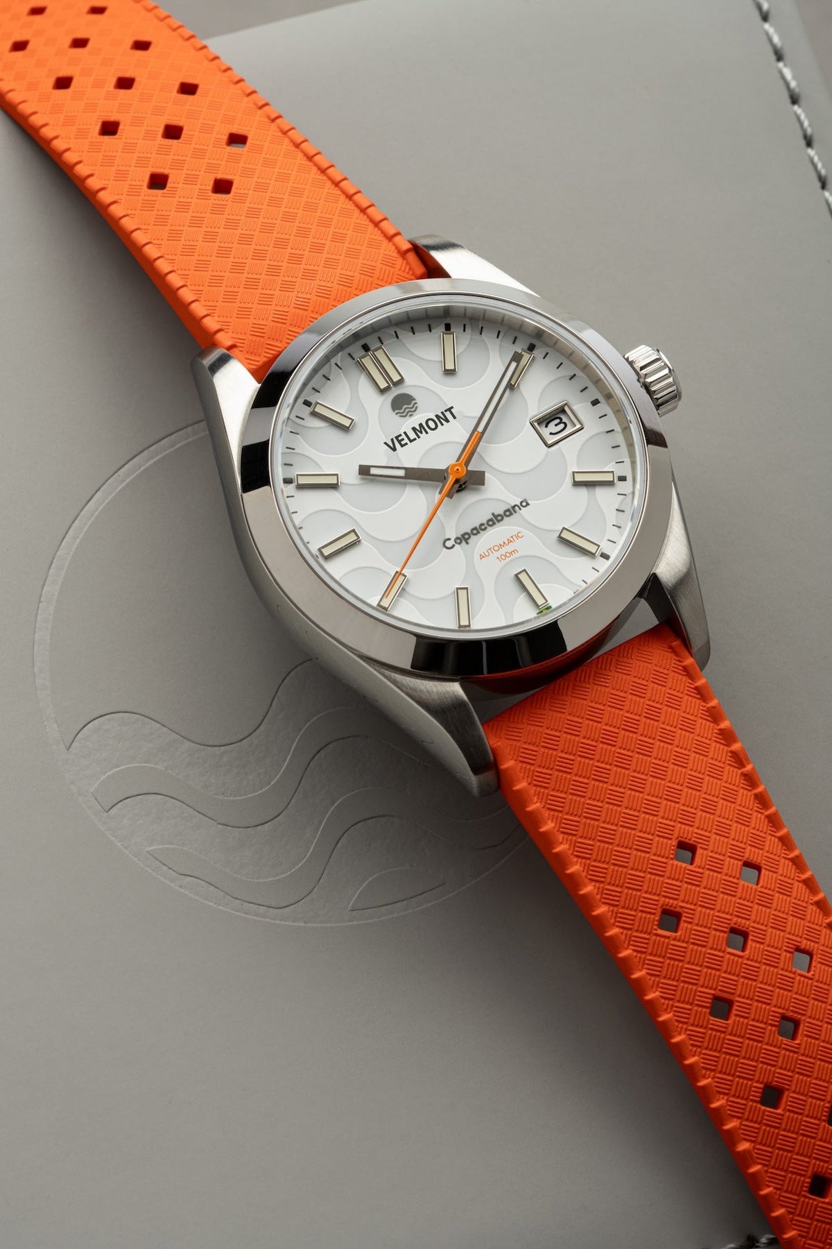 White dial watch on orange strap at an angle