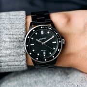 Worn on a wrist with a gray sweater, black bracelet and dotted bezel.