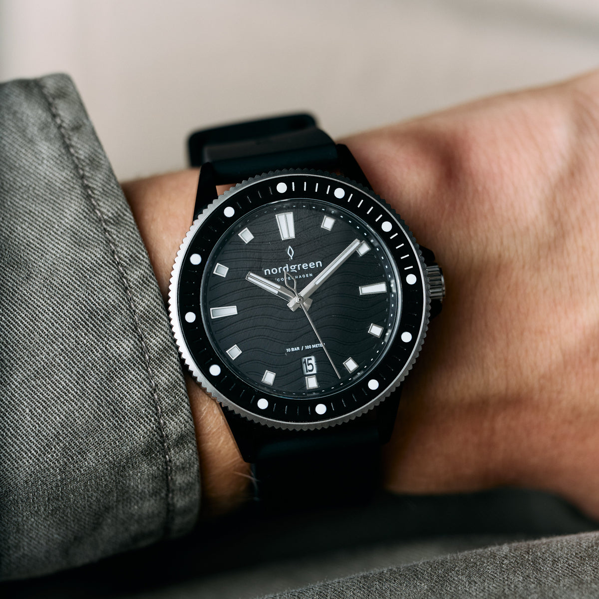 The black watch worn on a wrist beside a gray sleeve.