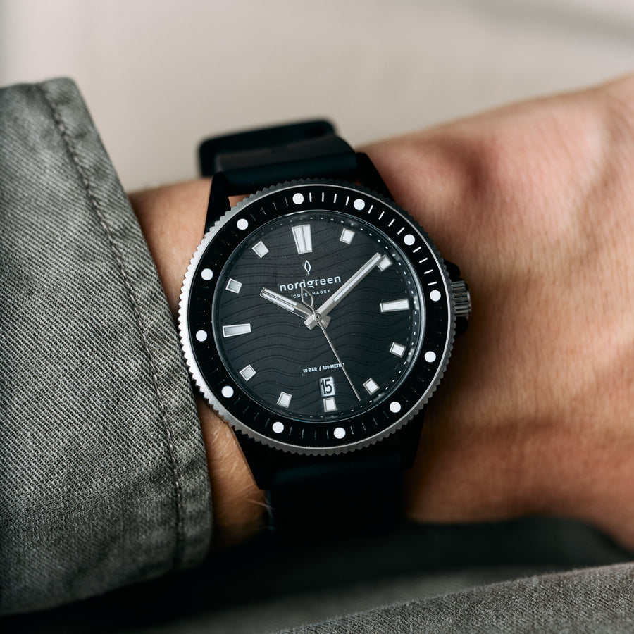 The black watch worn on a wrist beside a gray sleeve.