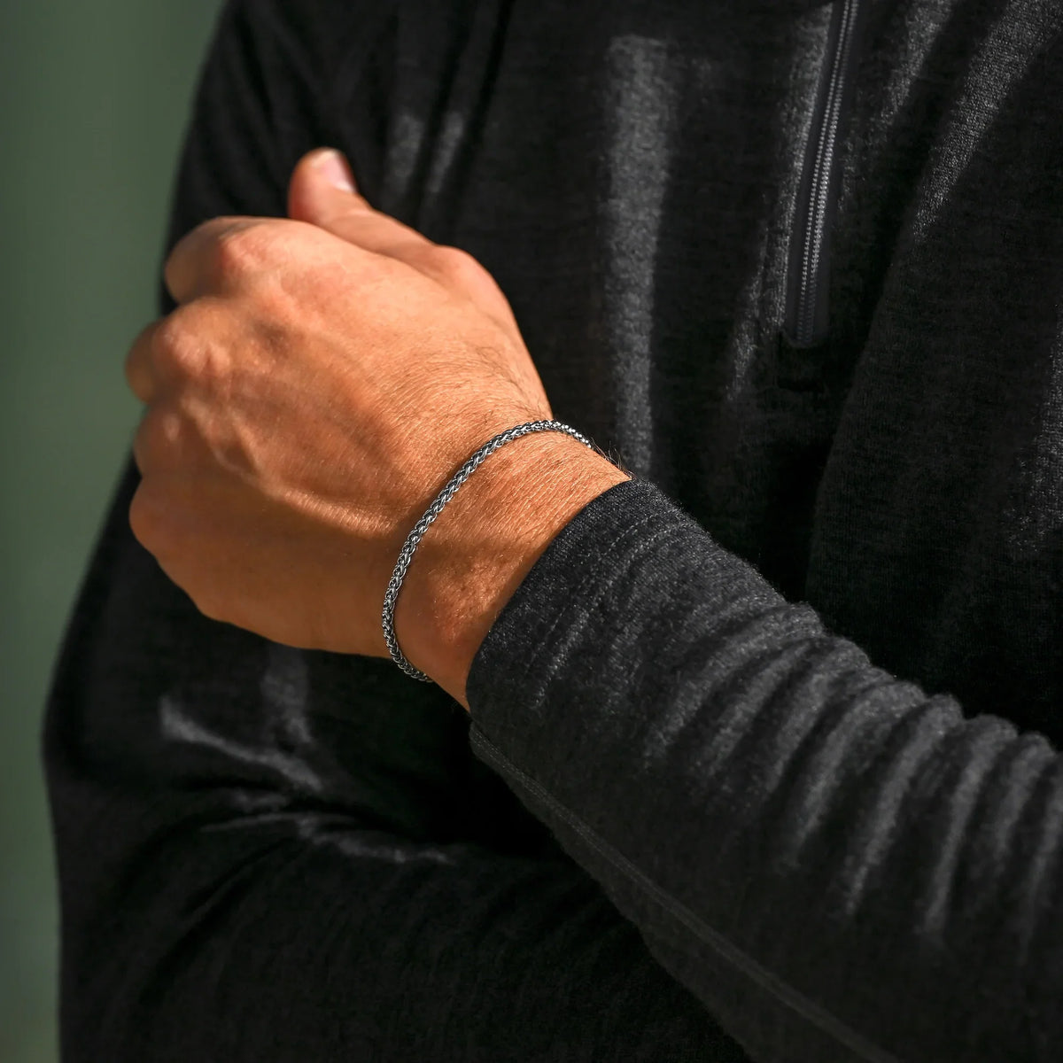 Wheat chain bracelet worn with a dark sweater