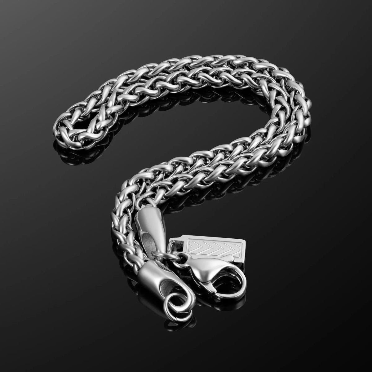 Coiled silver-tone wheat chain on a dark surface