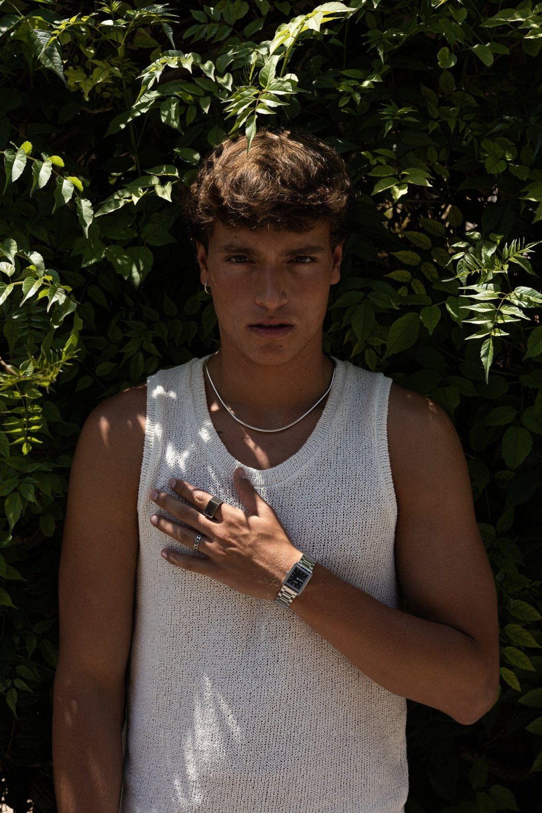 Man by green leaves with the watch on his wrist