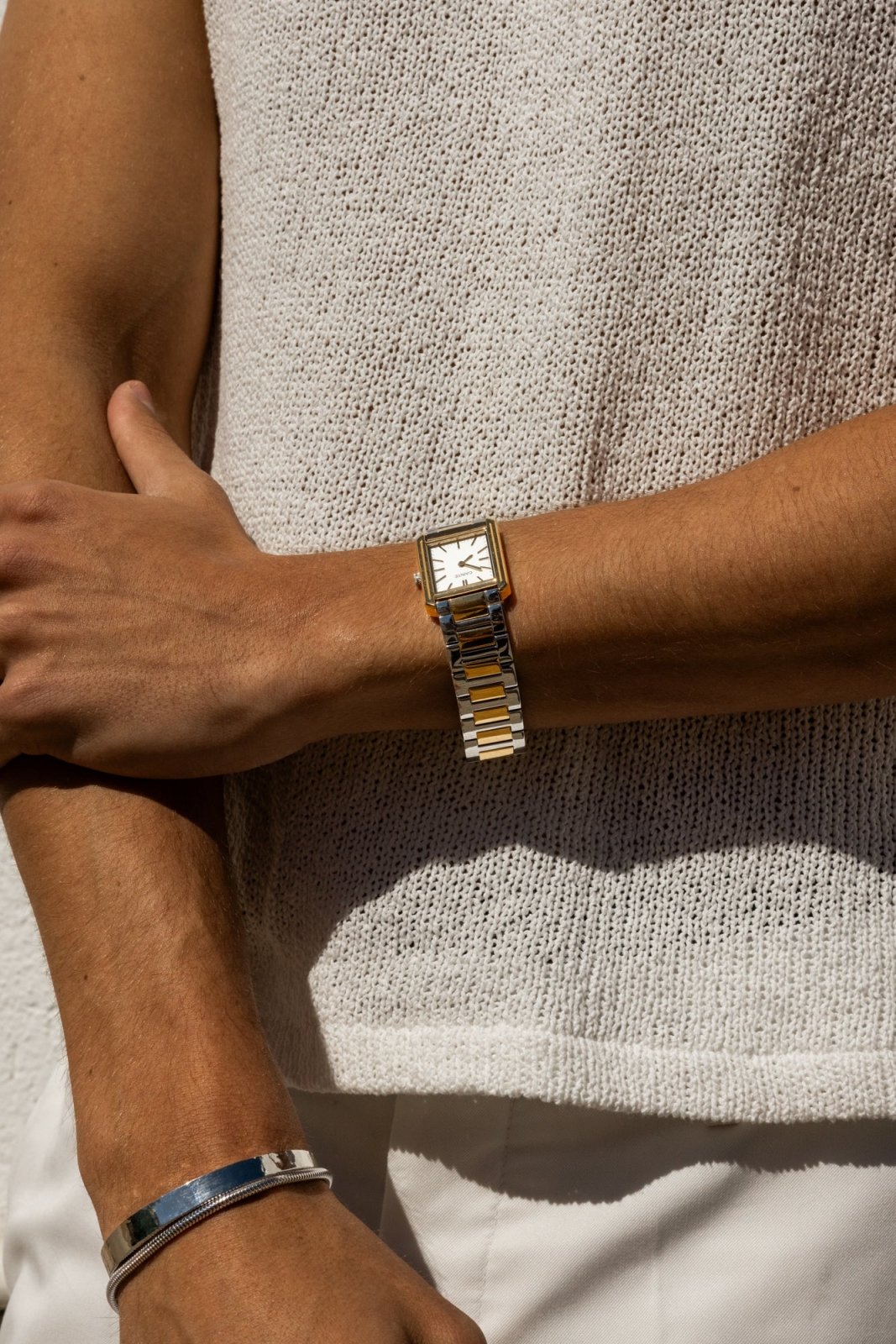 Arm across a knit top, gold-tone watch visible