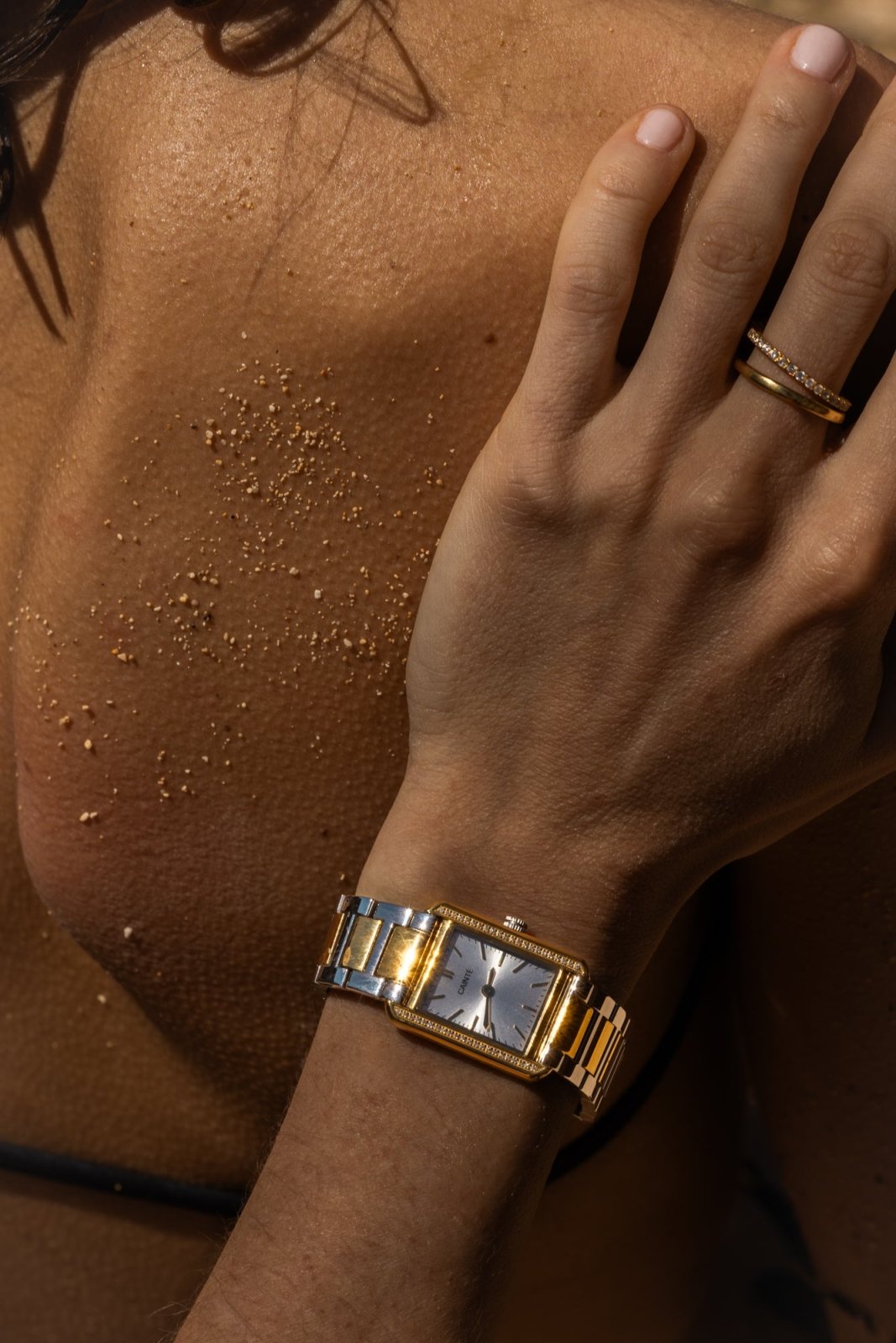 Hand on a sun-kissed shoulder wearing the two-tone watch