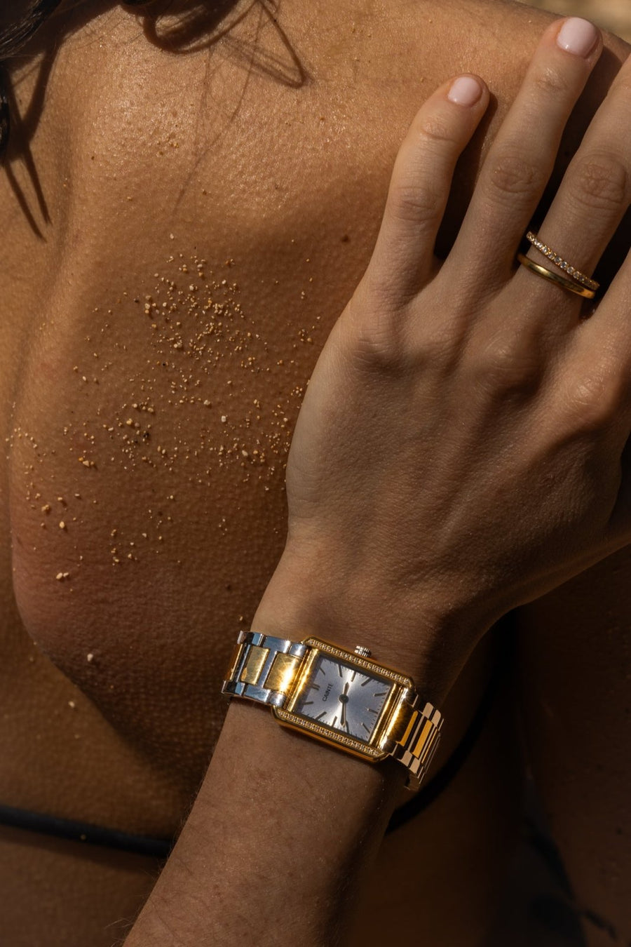 Hand on a sun-kissed shoulder wearing the two-tone watch