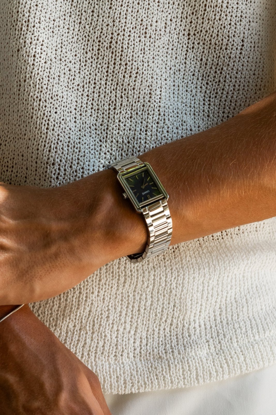 Wrist in a knit sweater wearing the rectangular watch