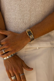 Hands crossed over a knit top, two-tone watch visible