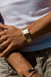 Hands crossed over a white T-shirt, watch on the wrist
