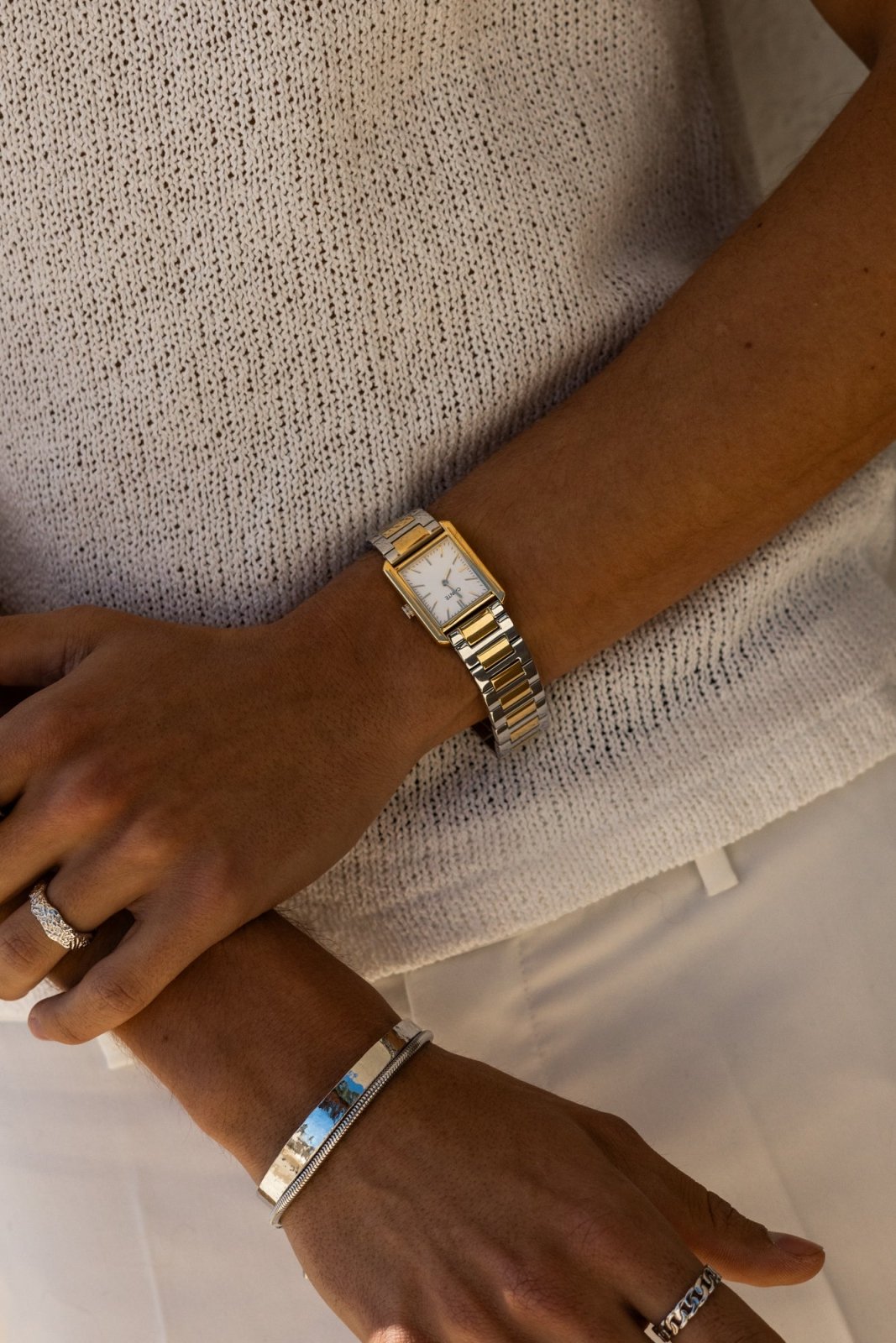 Arms crossed over a knit top, watch on the wrist