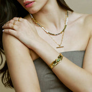 Green stone cuff worn with layered necklaces
