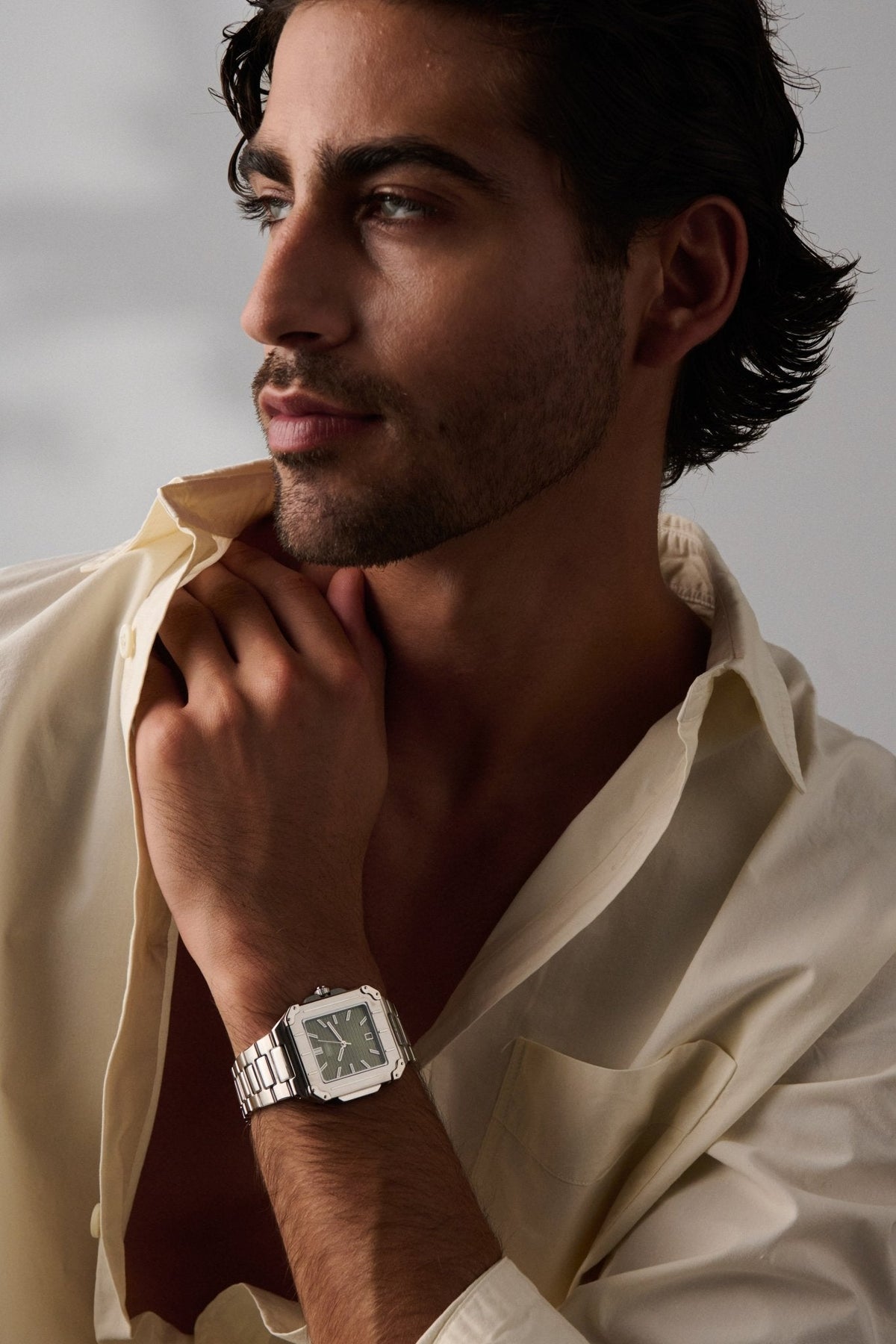 Man resting his chin on his hand, square watch on the wrist