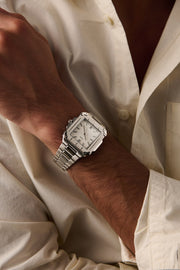 Square watch on a wrist in an open cream shirt