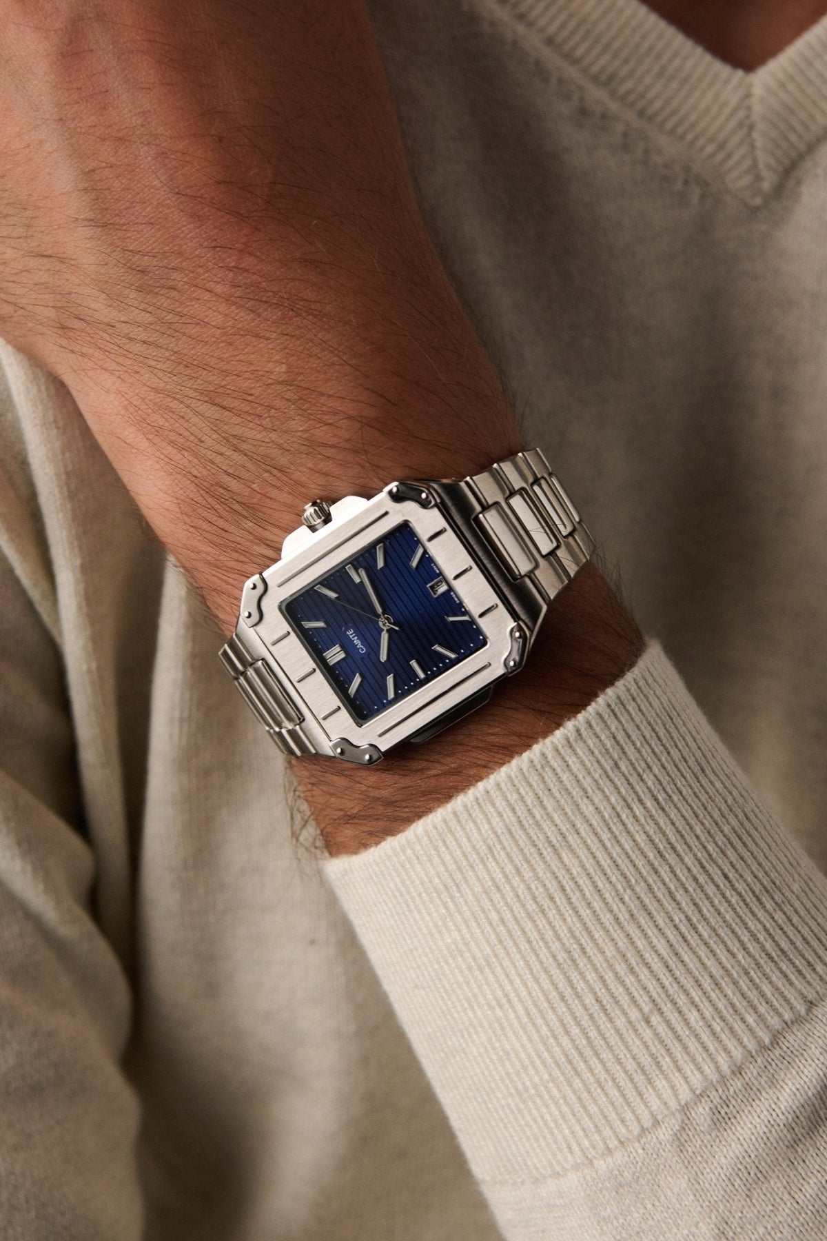 Square watch on a wrist in a cream sweater