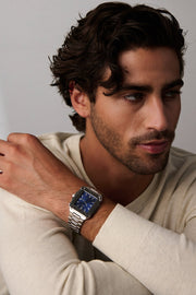 Man with arm raised to his shoulder wearing the square watch