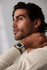Man in profile, hand at his neck, wearing the square watch