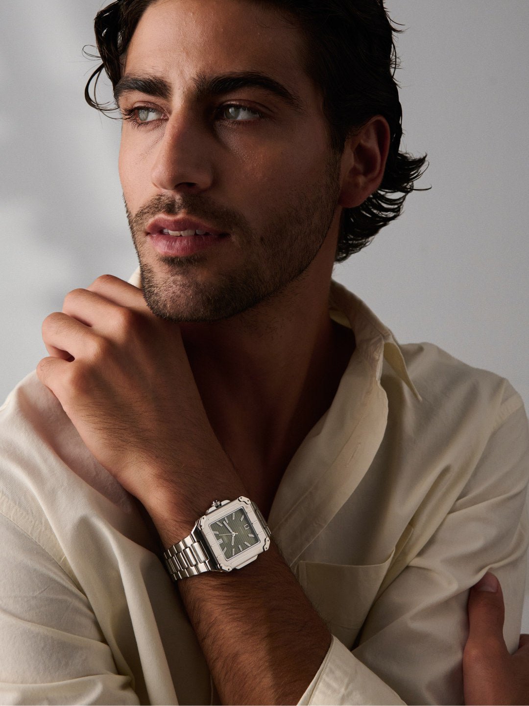 Man resting his chin on his hand, square watch on the wrist