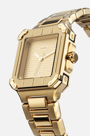Angled view of the square case with screw details at the corners and gold-tone dial