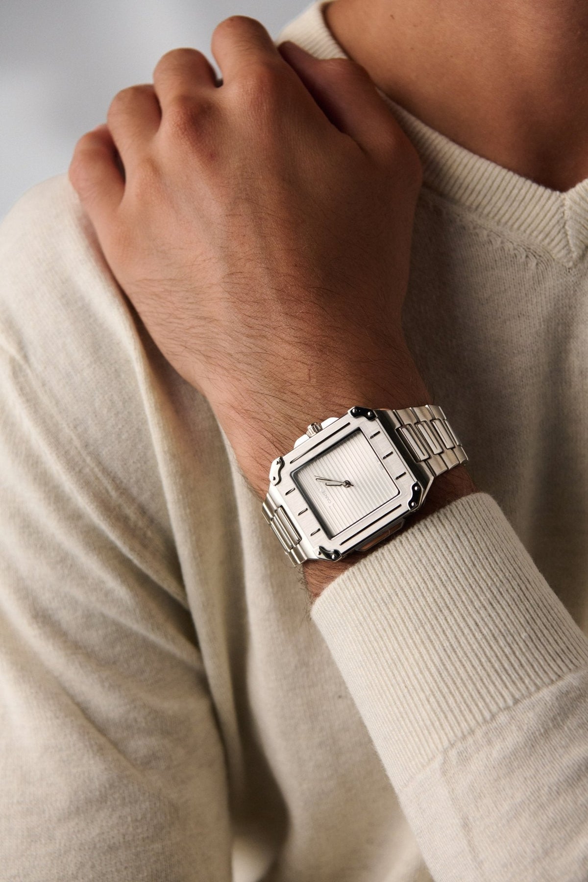 Square watch on a wrist in a cream sweater