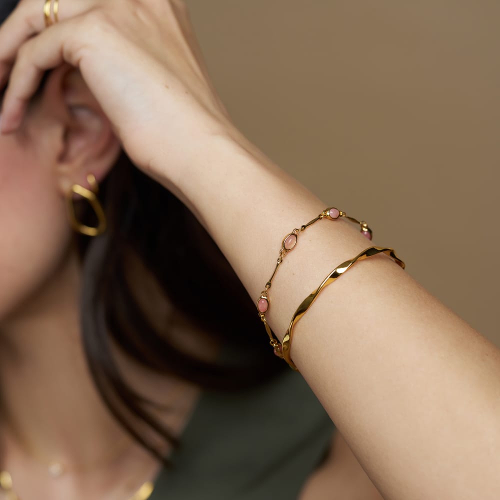 Pink stone bracelet worn with a gold bangle