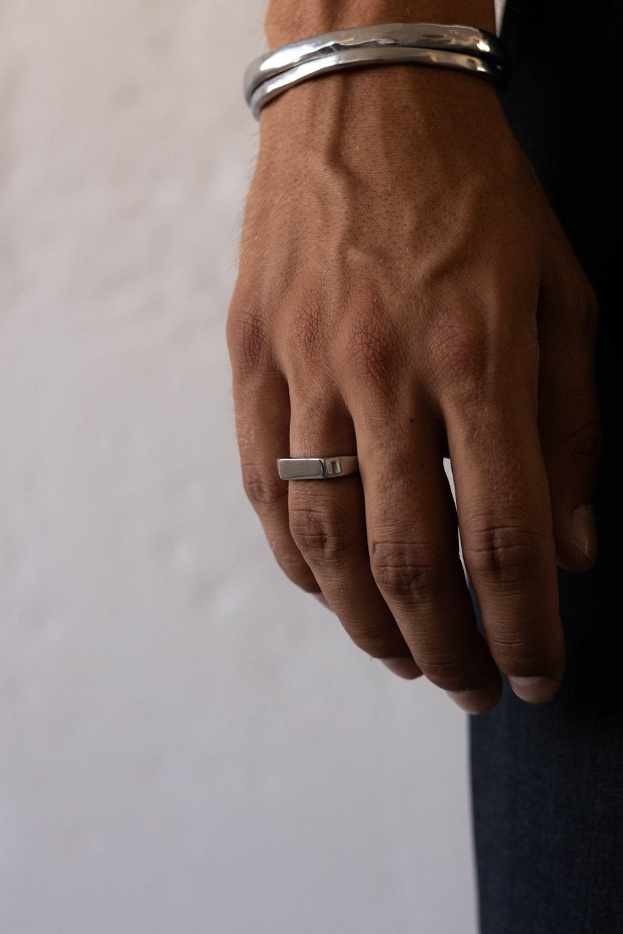 Man’s hand wearing the signet ring and a bangle