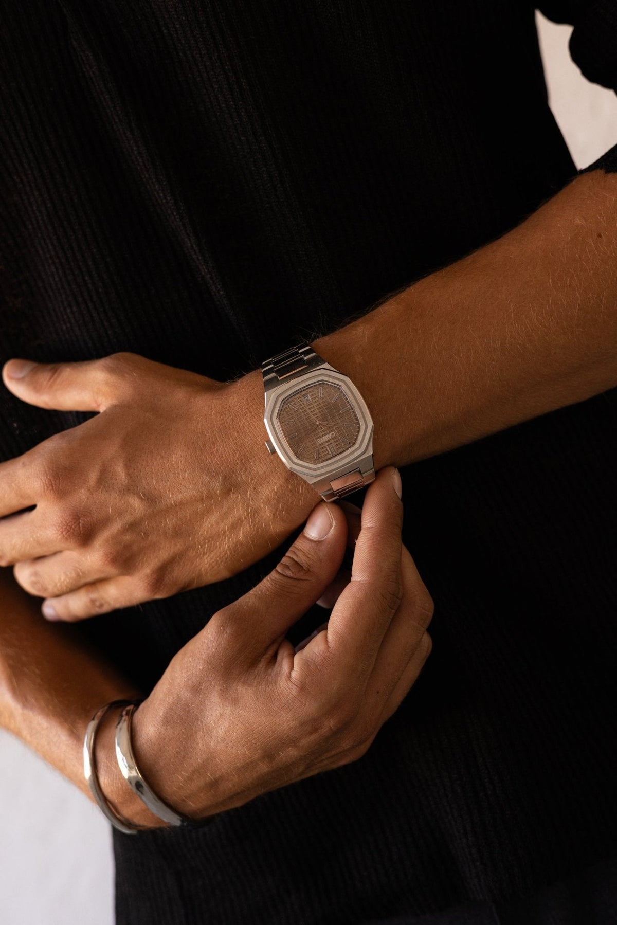Hand adjusting the watch over a black shirt