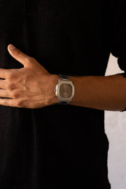 Hands crossed over a black shirt, watch visible