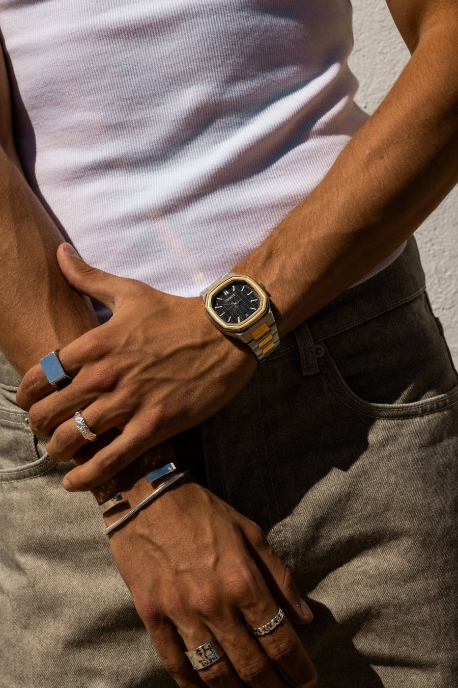 Hands crossed over gray jeans, watch on the wrist
