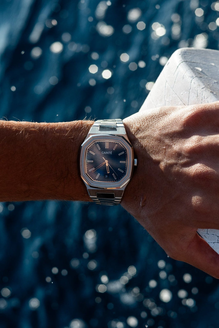 Wrist over sparkling sea water wearing the watch