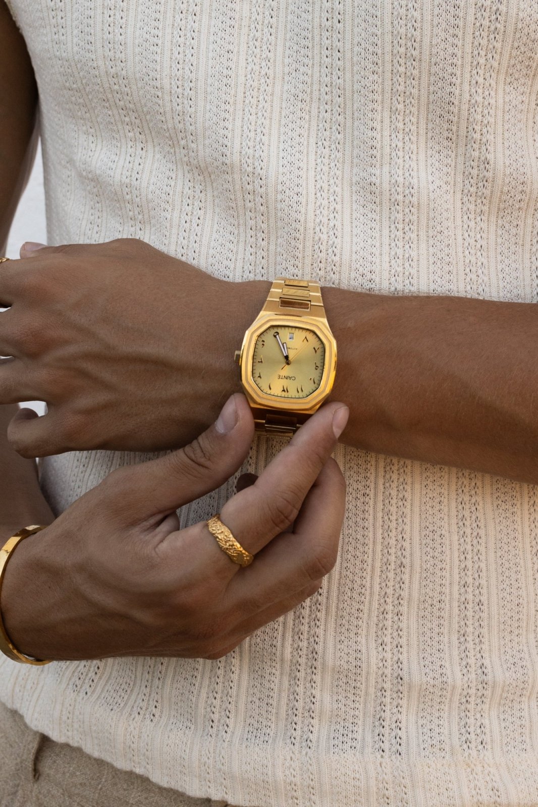 Hand adjusting the watch over a ribbed knit tank