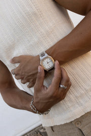 Fingers on the watch against a ribbed knit top